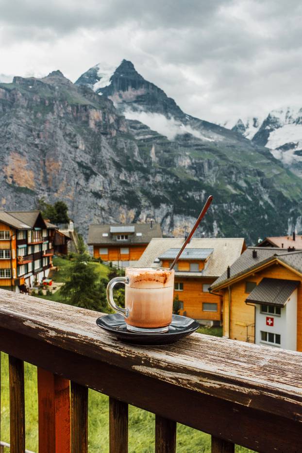 Switzerland, Jungfrau. Swiss Alps. Cozy traditional small village in mountains. Cafe terrace. Morning hot cup of coffee.