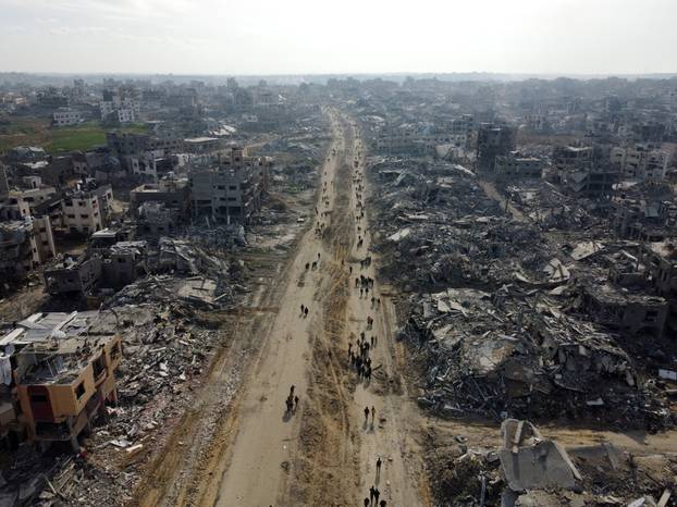 Displaced Palestinians walk past the rubble as they attempt to return to their homes, in the northern Gaza Strip