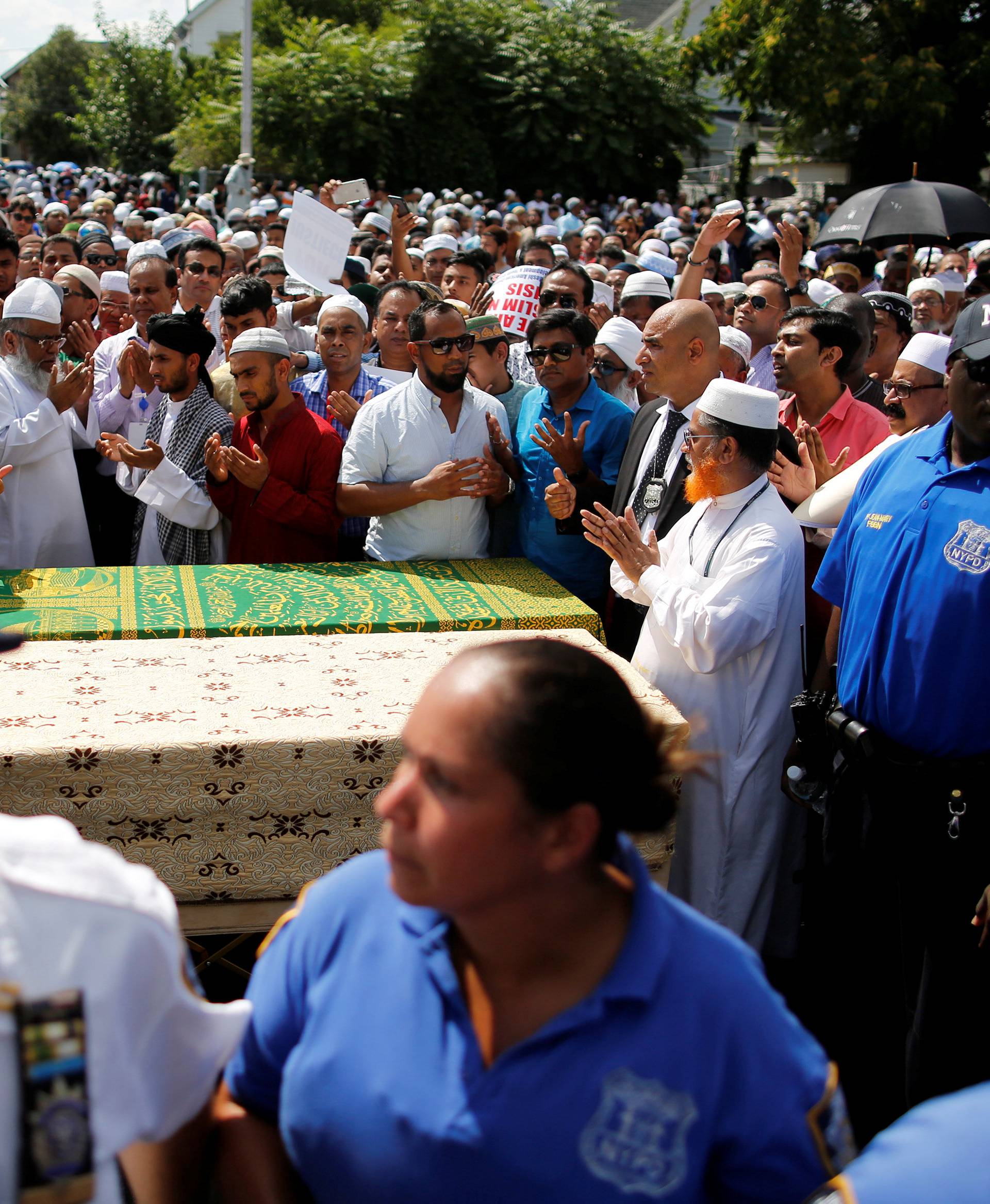 Community members pray next to the coffins during the funeral service of Akonjee, and Uddin in the Queens borough of New York City