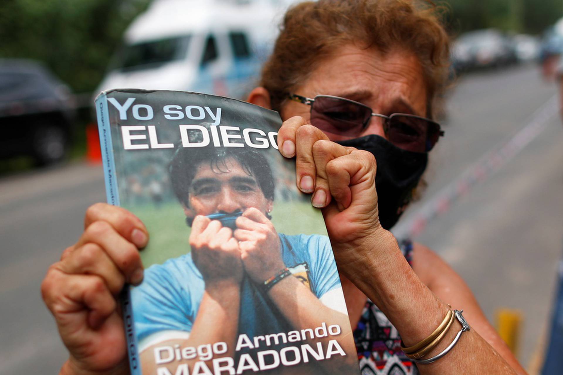 Woman holds a book "Yo soy el Diego" outside the house where Diego Maradona was staying, in Tigre