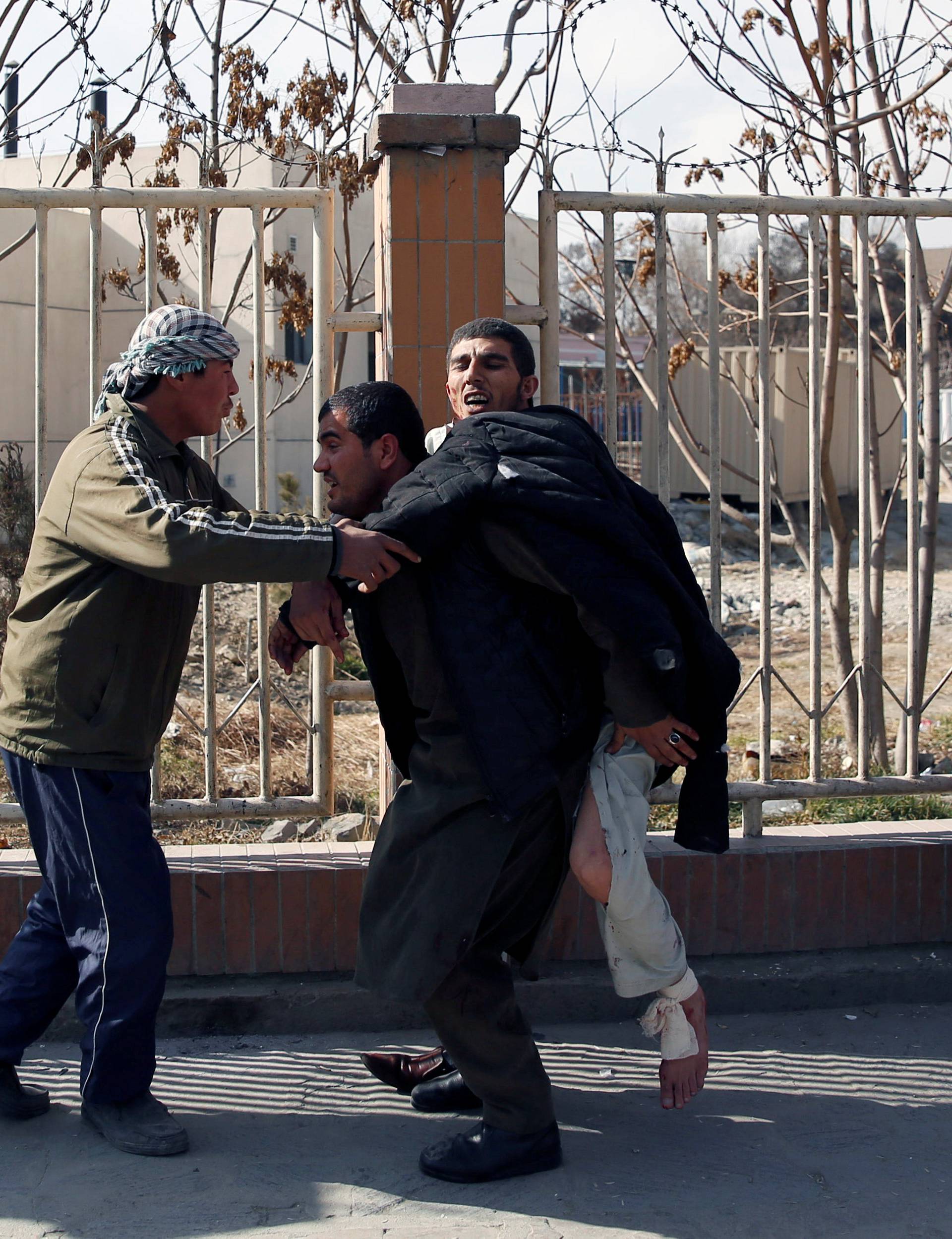 Injured man is carried after a blast in Kabul