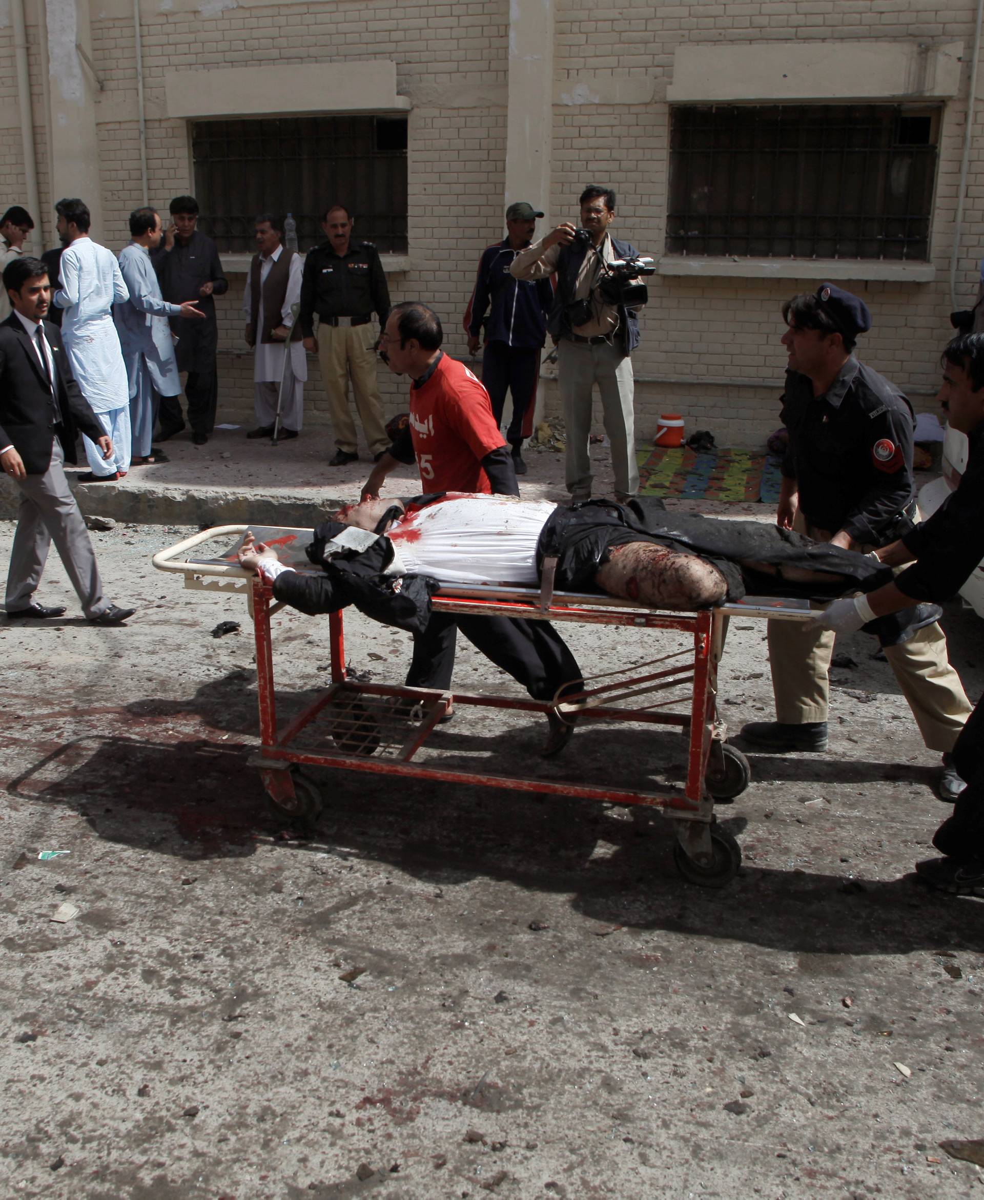 Police and hospital staff move a victim of a bomb blast, outside a hospital in Quetta