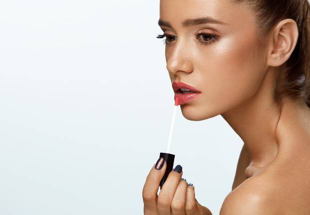 Beautiful Woman Doing Makeup Using Lip Gloss On Lips. Cosmetics