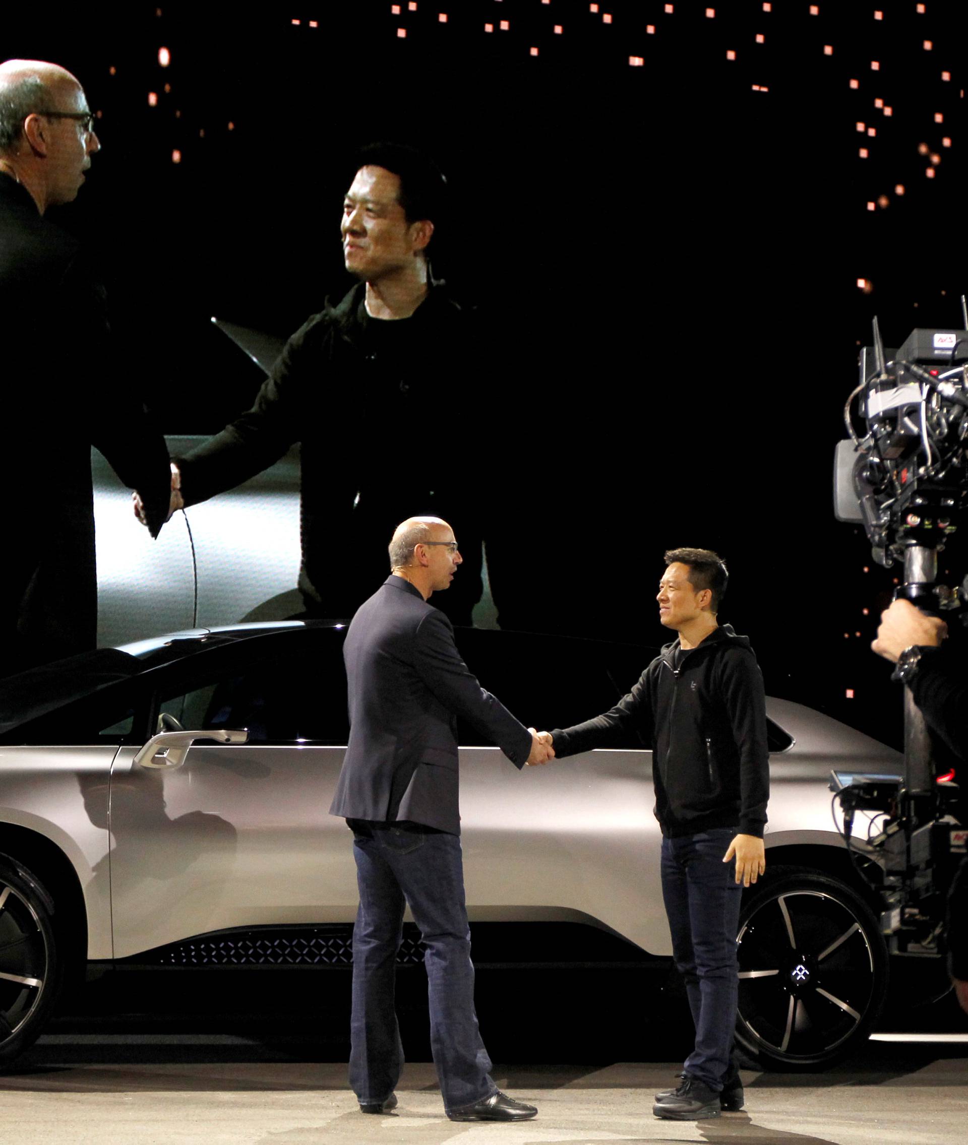 Nick Sampson (L), senior vice president of product R&D and engineering at Faraday Future, shakes hands with YT Jia (L), founder and CEO of LeEco, in front of a Faraday Future FF 91 electric car during an unveiling event in Las Vegas