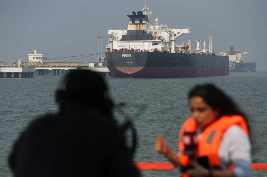Journalists report in front of the Liberia-flagged tanker Shenlong Suezmax, loaded with Saudi Arabian crude, after it arrived at a port after transiting the Strait of Hormuz amid supply disruptions linked to the U.S-Israeli conflict with Iran