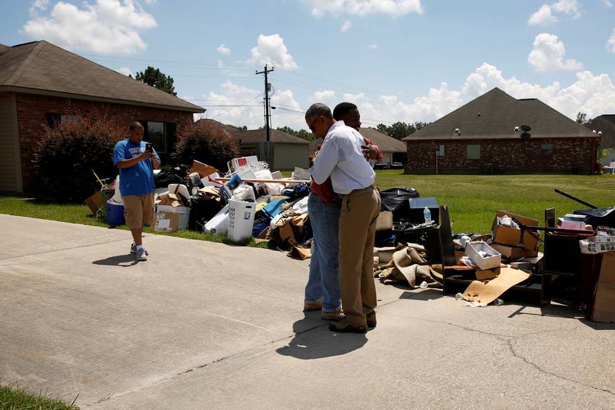 U.S. President Barack Obama greets a homeowner as he tours a flood-affected neighborhood in Zachary