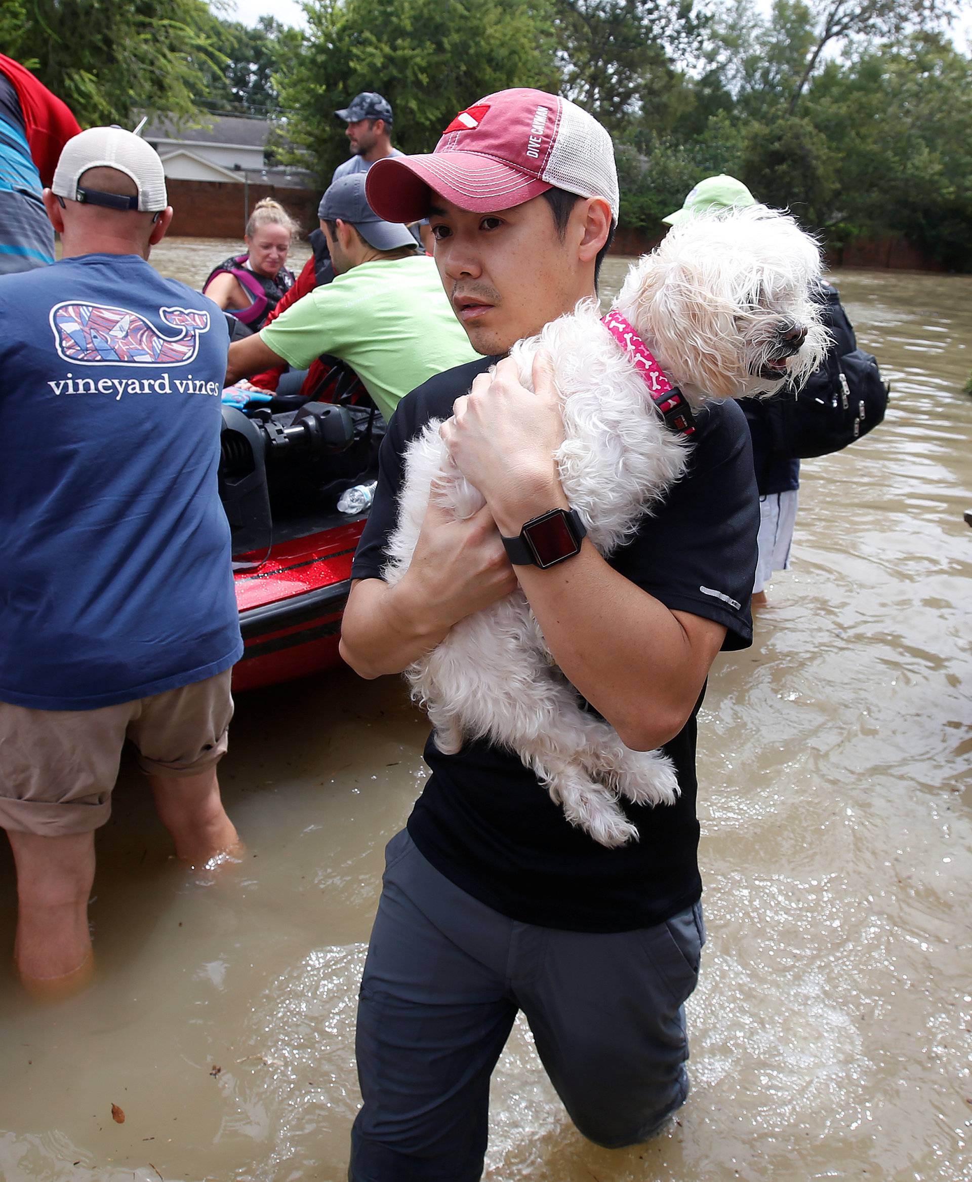 A man carries a dog from a rescue boat as it evacuates people from the rising waters of Buffalo Bayou following Hurricane Harvey in a neighborhood west of Houston