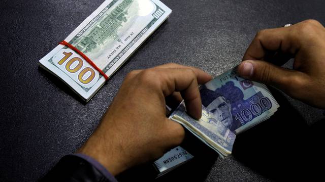 FILE PHOTO: A currency trader counts Pakistani Rupee notes as he prepares an exchange of U.S dollars in Islamabad