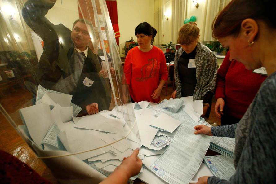 Members of a local election commission empty a ballot box before starting to count votes during the presidential election at a polling station in a settlement in Smolensk Region
