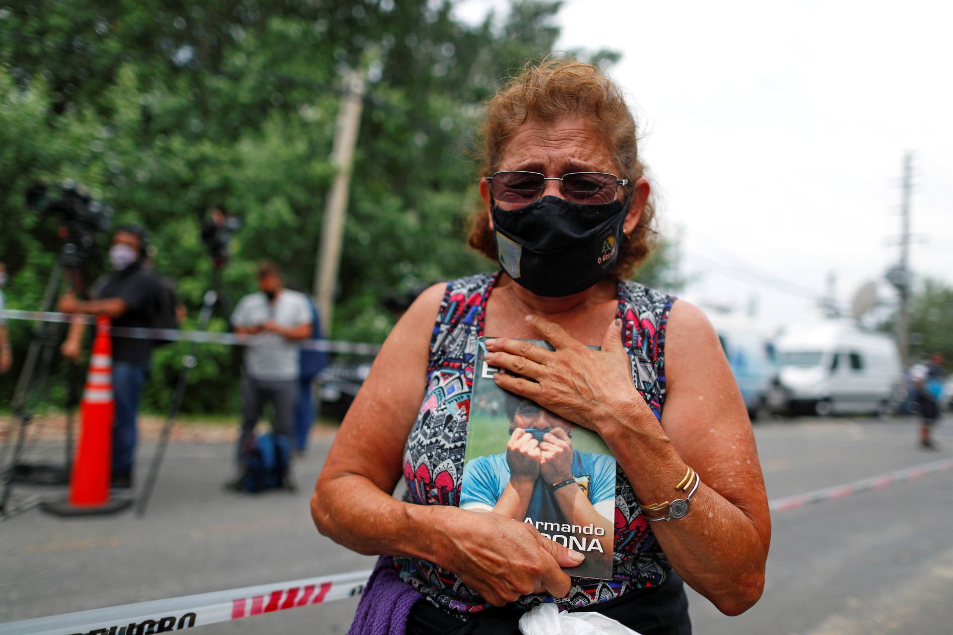 Woman holds a book "Yo soy el Diego" outside the house where Diego Maradona was staying, in Tigre