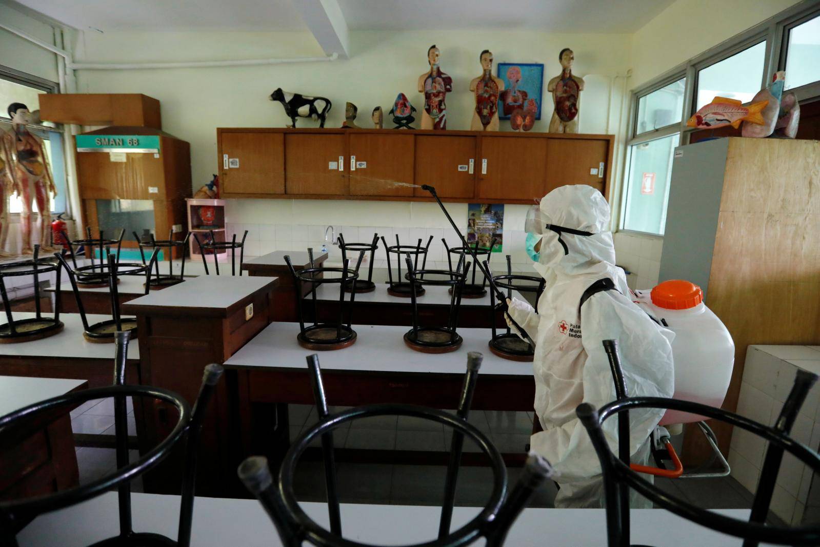 A volunteer from Indonesia's Red Cross sprays disinfectant inside the laboratorium of a school closed amid the spread of coronavirus in Jakarta