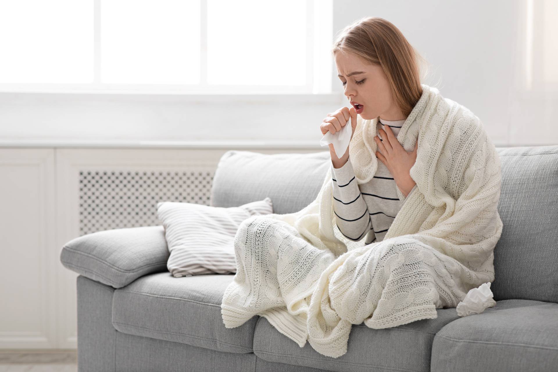 Sick young woman coughing at home, empty space