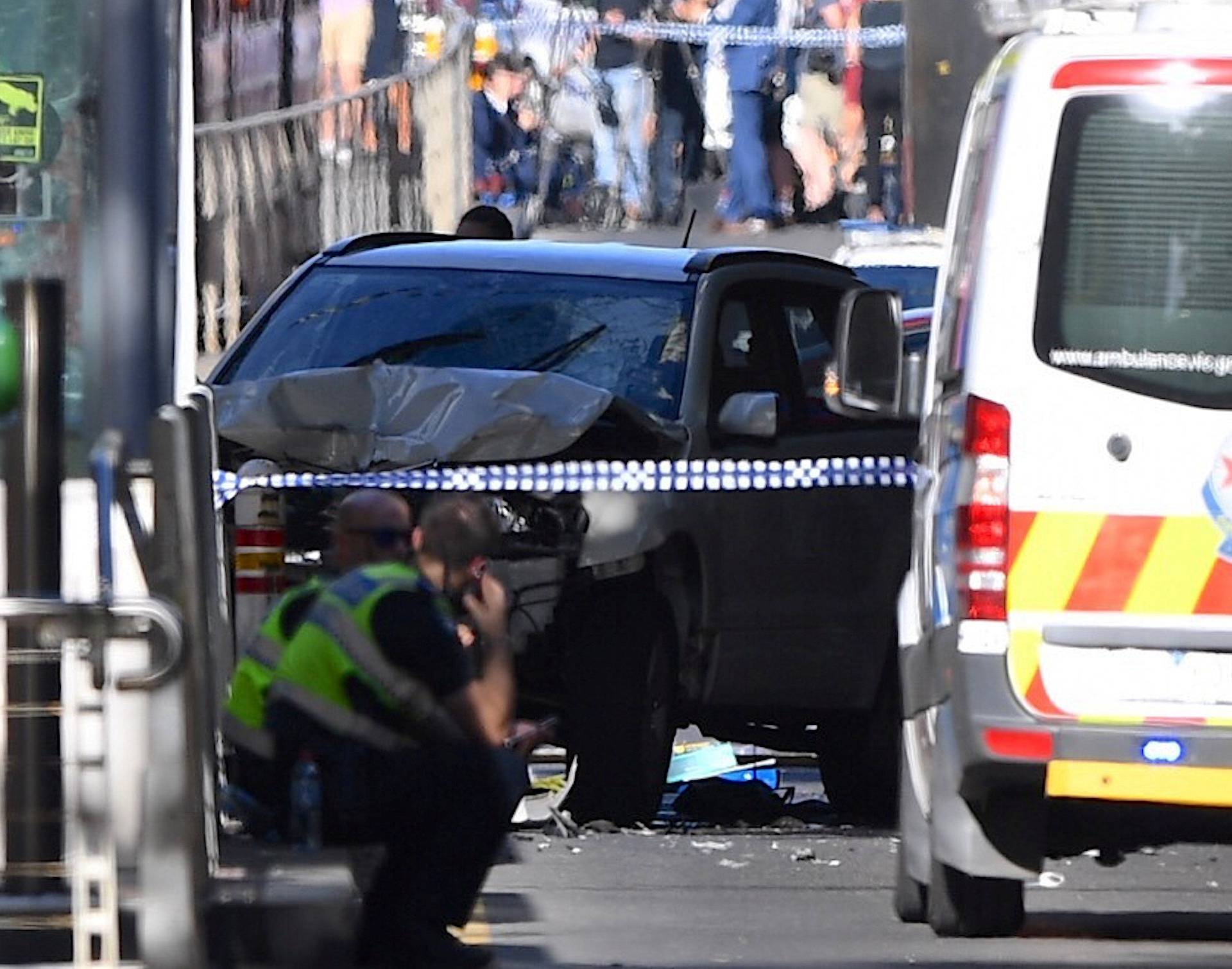 Police sit in front of a crashed vehicle after a driver was arrested after ploughing into pedestrians at a crowded intersection near the Flinders Street train station in central Melbourne
