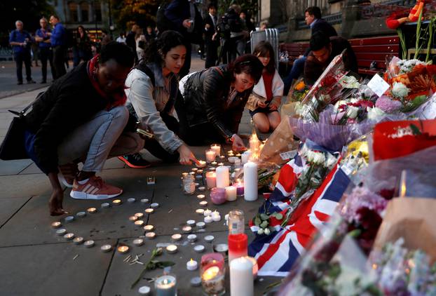 Women light candles for the victims of the Manchester Arena attack, in central Manchester