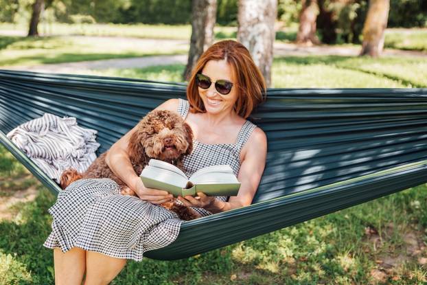 Woman,Reading,Book,Relaxing,In,Hammock,With,Her,Fluffy,Brown