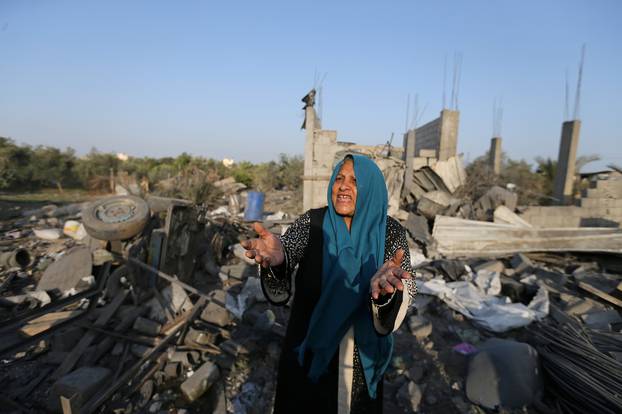 Palestinian woman reacts as she inspects a house destroyed in an Israeli air strike in the southern Gaza Strip