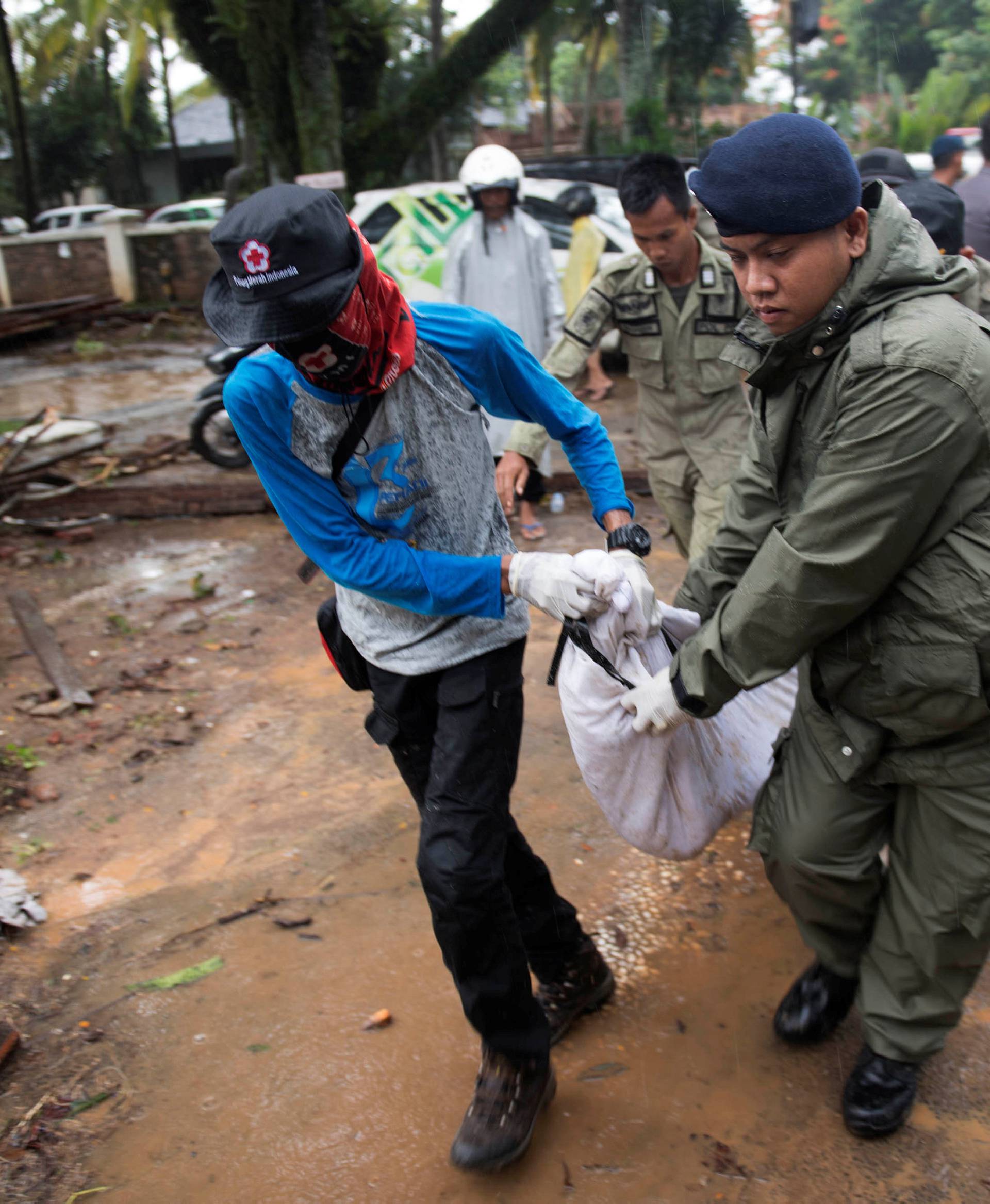 Rescue team members carry the dead body of a victim after a tsunami hit Tanjung Lesung beach in Banten