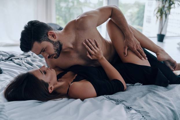 Pure passion. Beautiful young couple touching each other while lying in bed together