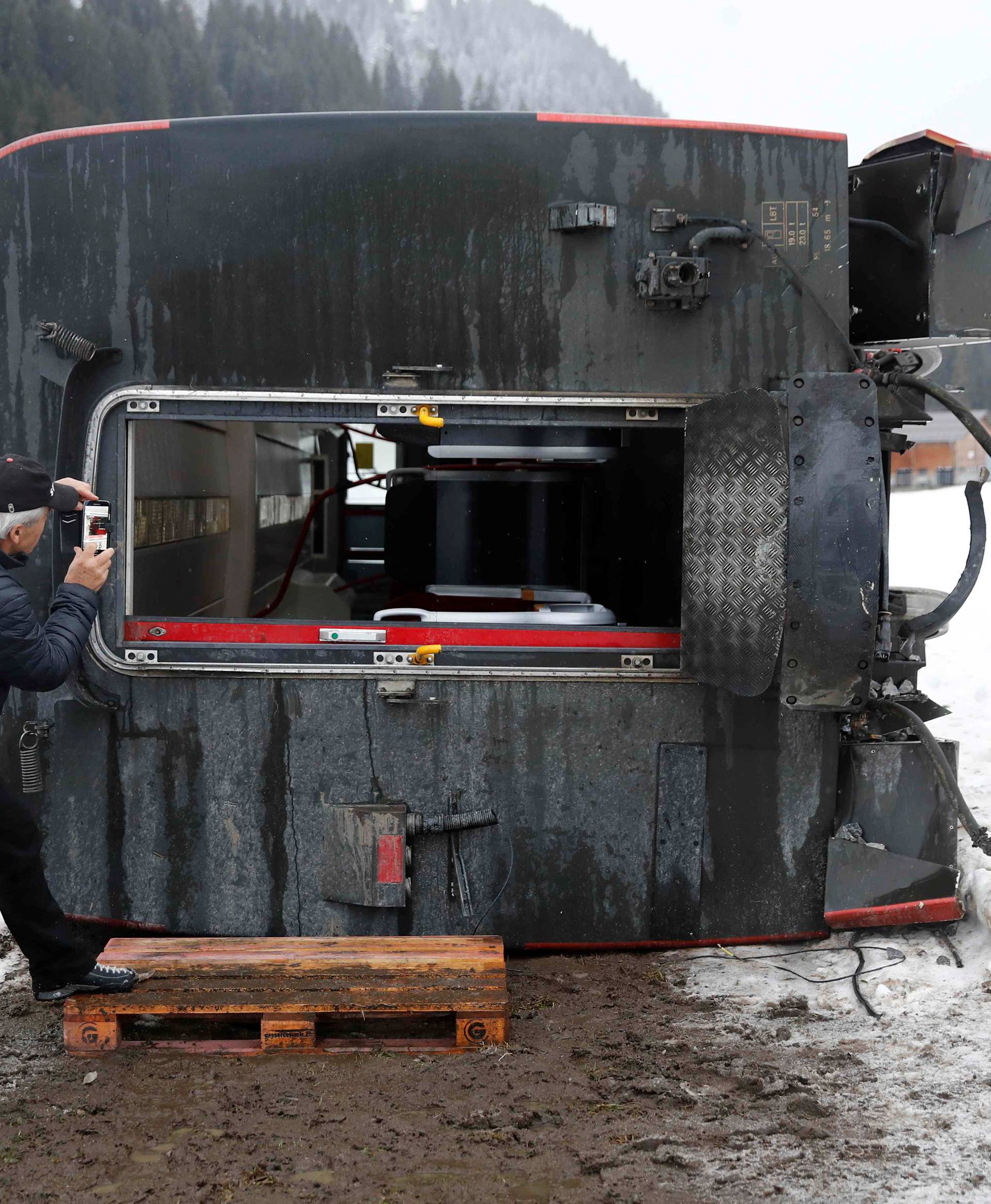 A man takes pictures of a carriage of the MOB train lying on its side after if was pushed out of the tracks by gusts of wind during storm Eleanor near Lenk