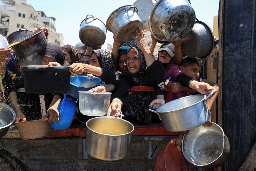 Palestinians wait to receive food from a charity kitchen, in Gaza City