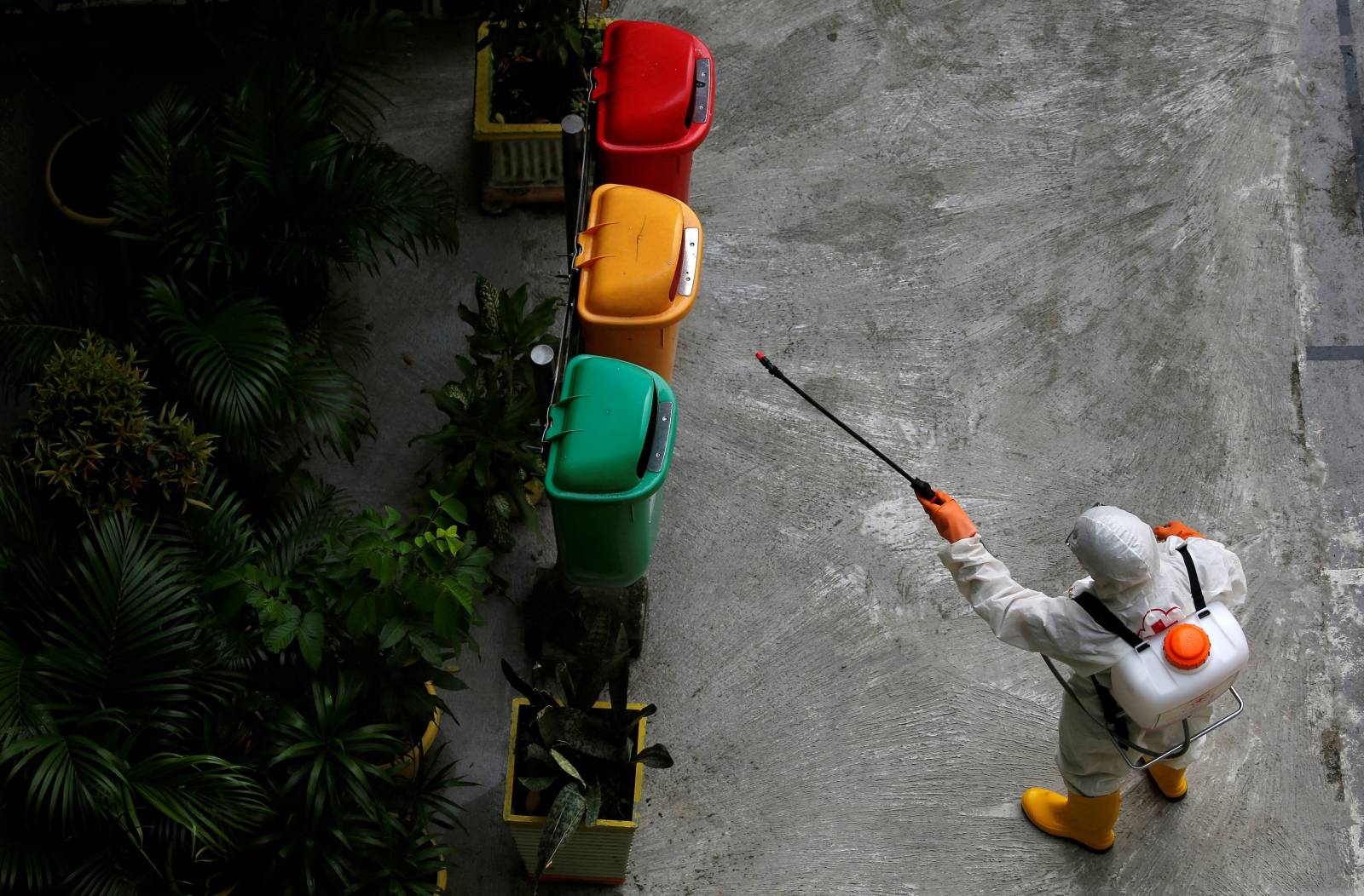 A volunteer from Indonesia's Red Cross sprays disinfectant on trash bins at a school closed amid the spread of coronavirus in Jakarta