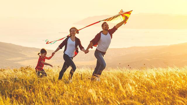 Happy family father,  mother and child daughter launch a kite on nature at sunset