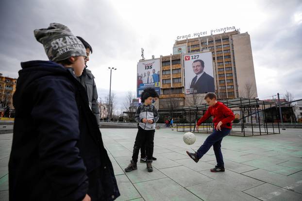 Children play football near electoral campaign billboards in Pristina, Kosovo