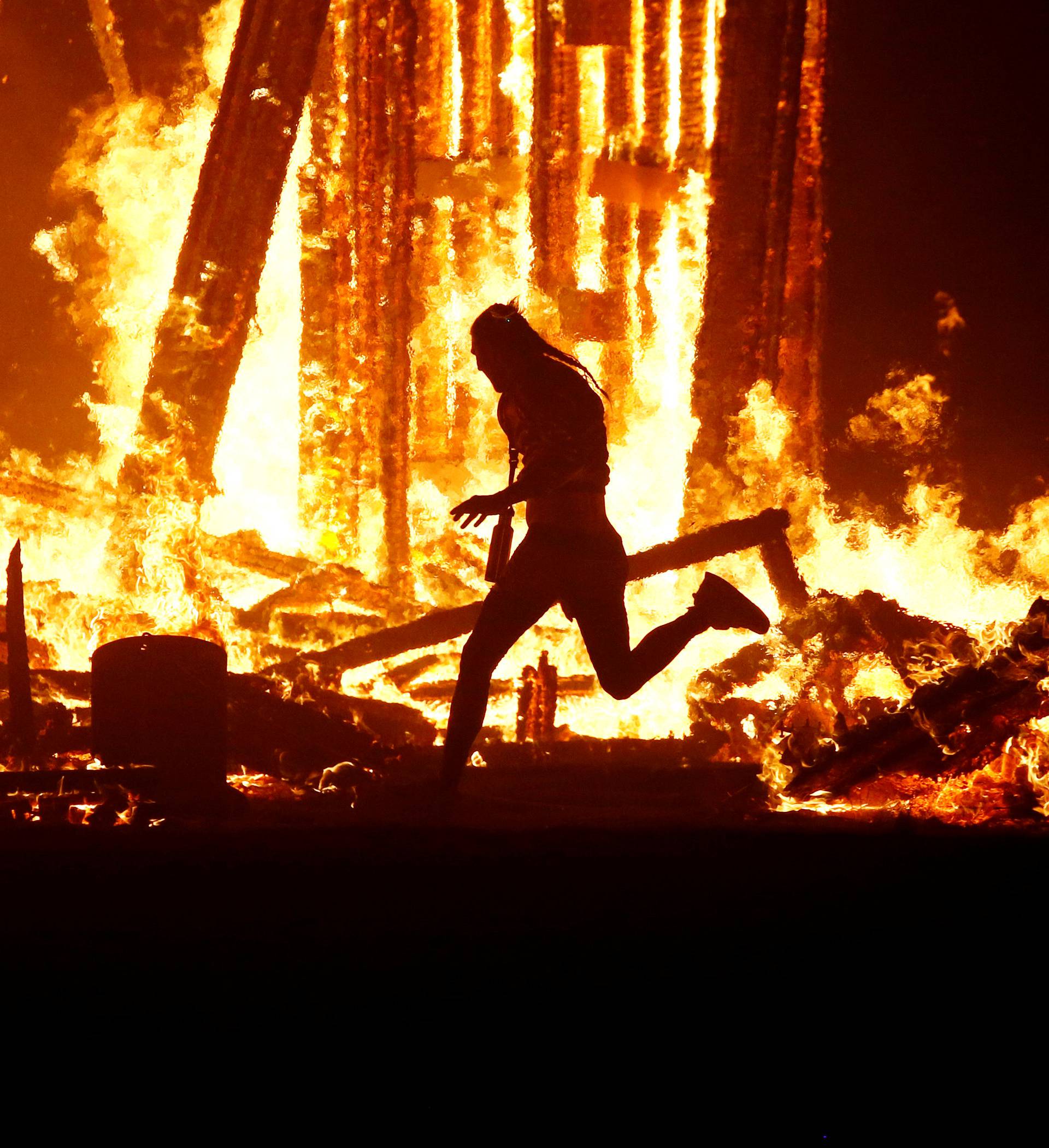 Burning Man participant runs into the flames of the "Man Burn" at the Burning Man arts and music festival in the Black Rock Desert of Nevada