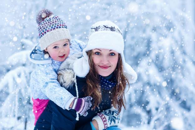 little girl and her mother in winter forest with snow
