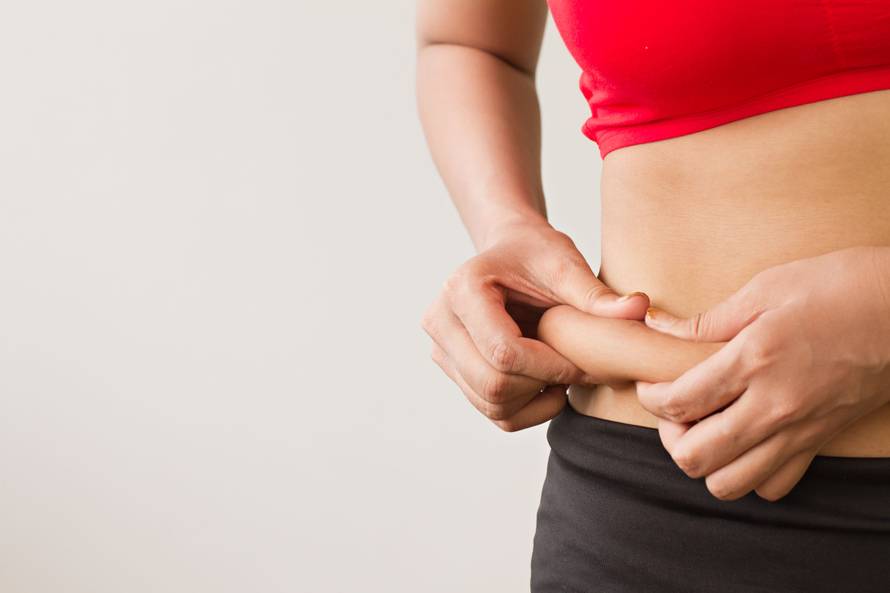 woman's hand holding excessive belly fat