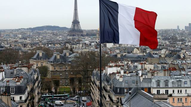 FILE PHOTO: A French flag waves above the skyline as the Eiffel Tower and roof tops are seen in Paris, France