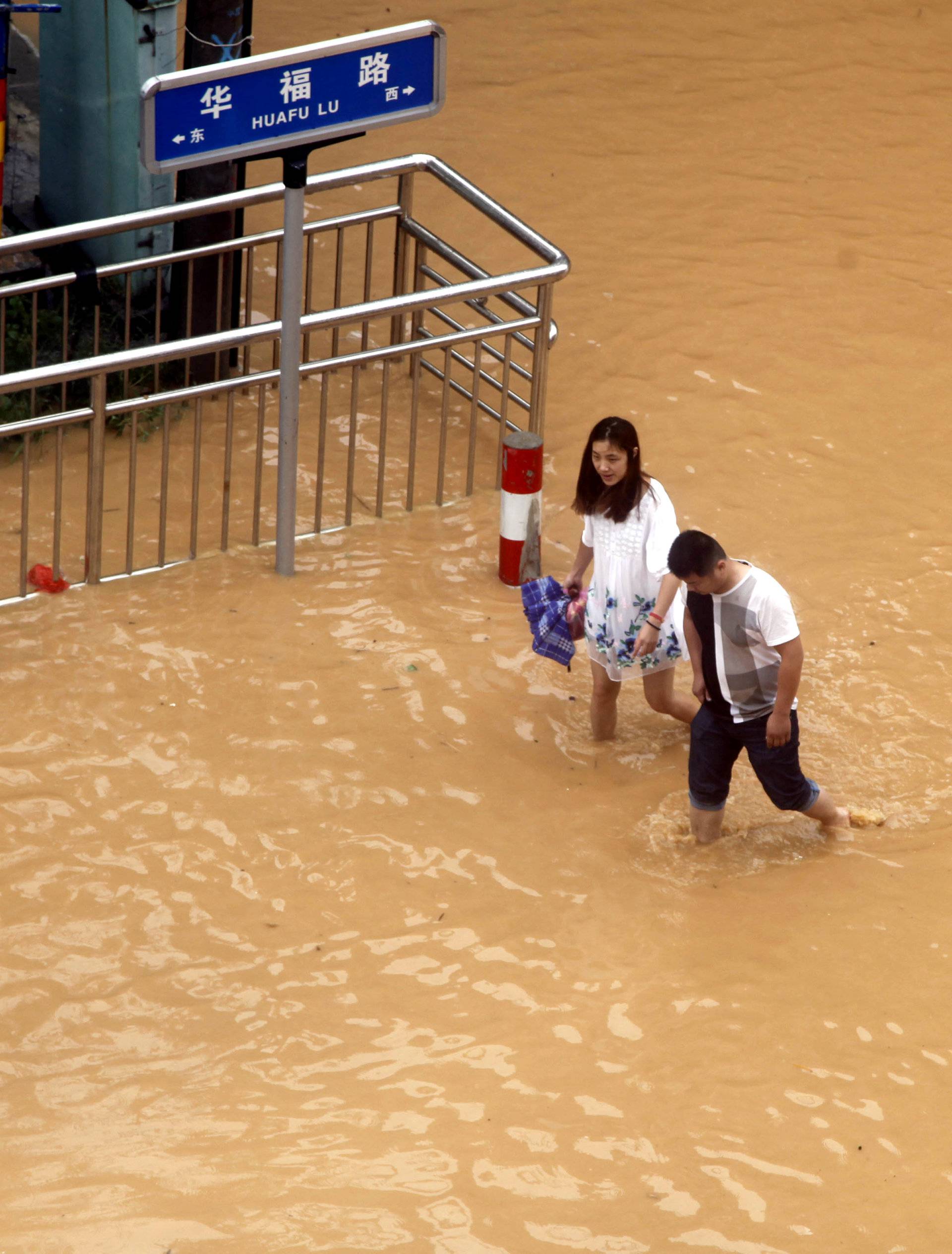 Residents walk at a flooded area as Typhoon Nepartak brings heavy rainfall in Putian