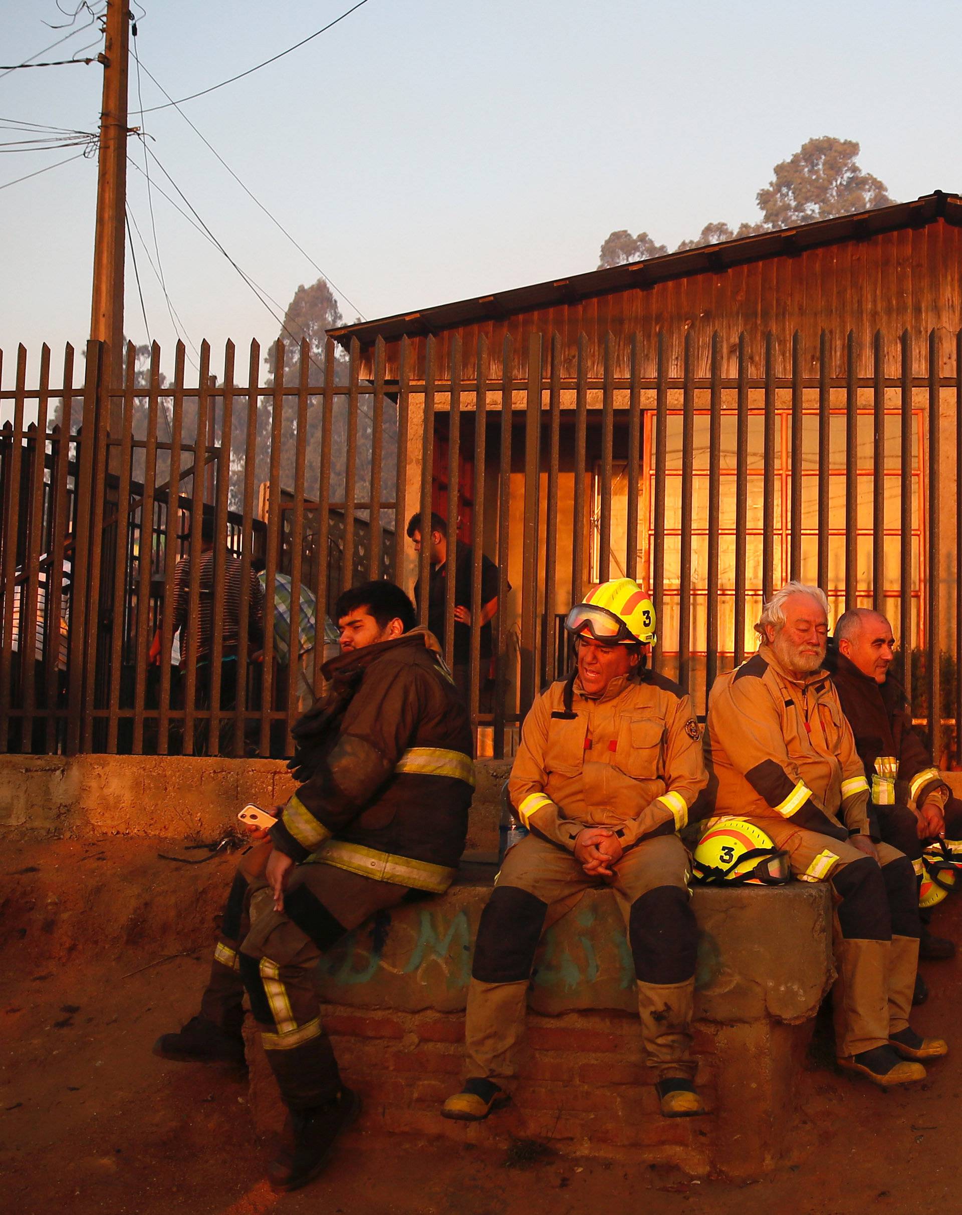 Firefighters are seen resting after working to extinguish fire on a hill, where more than 100 homes were burned due to a forest fire but there have been no reports of death, local authorities said in Valparaiso, Chile