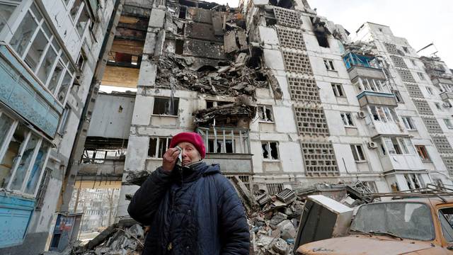 A local resident reacts next to the building where her destroyed apartment is located in the besieged city of Mariupol