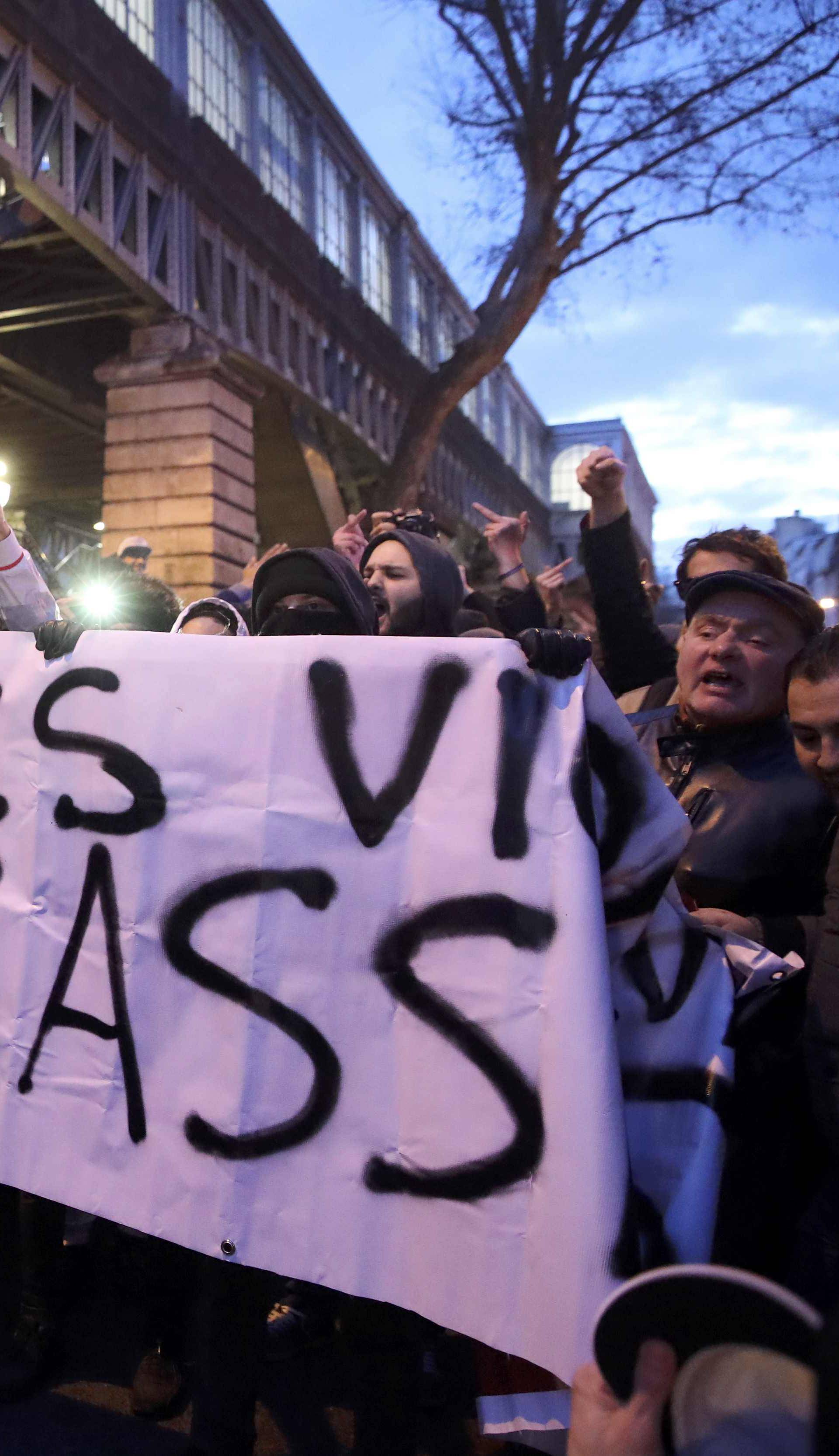 People hold a banner with the message that reads, "Cops Rapists Murderers" to protest police brutality as they gather at a deomostration in Paris 