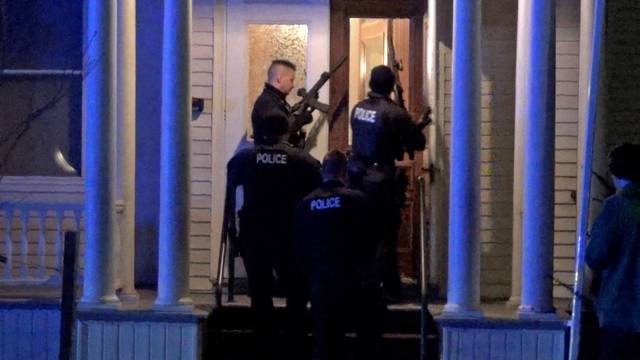 Police search a house in the neighbourhood after a gunman shot and wounded three college students of Palestinian descent in Burlington