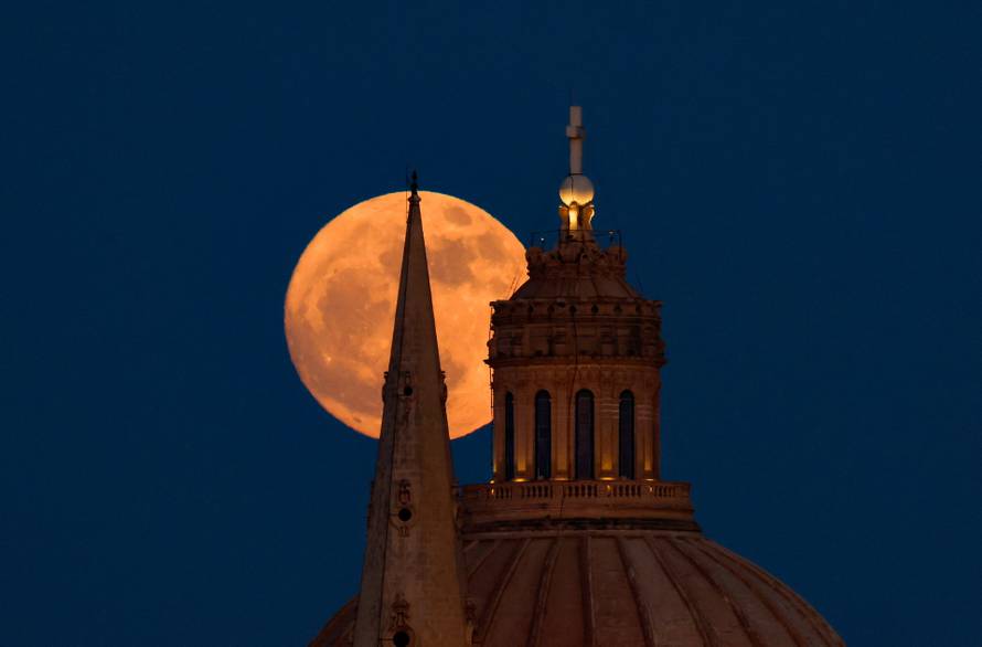 A full moon known as the Strawberry Moon rises behind St Paul's Anglican Cathedral and the Basilica of Our Lady of Mount Carmel in Valletta