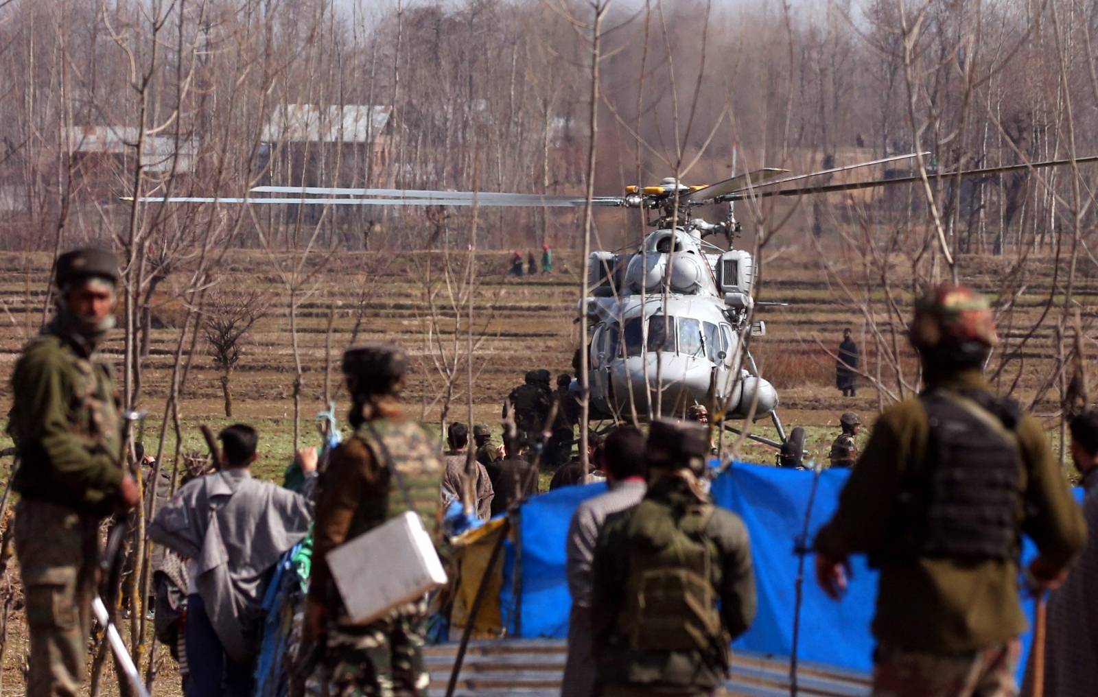 An Indian Air Force chopper lands as soldiers stand at the site after Indian Air Force's helicopter crashed in Budgam