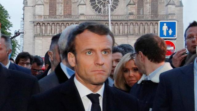 French President Emmanuel Macron walks near the Notre Dame Cathedral as its burns in Paris
