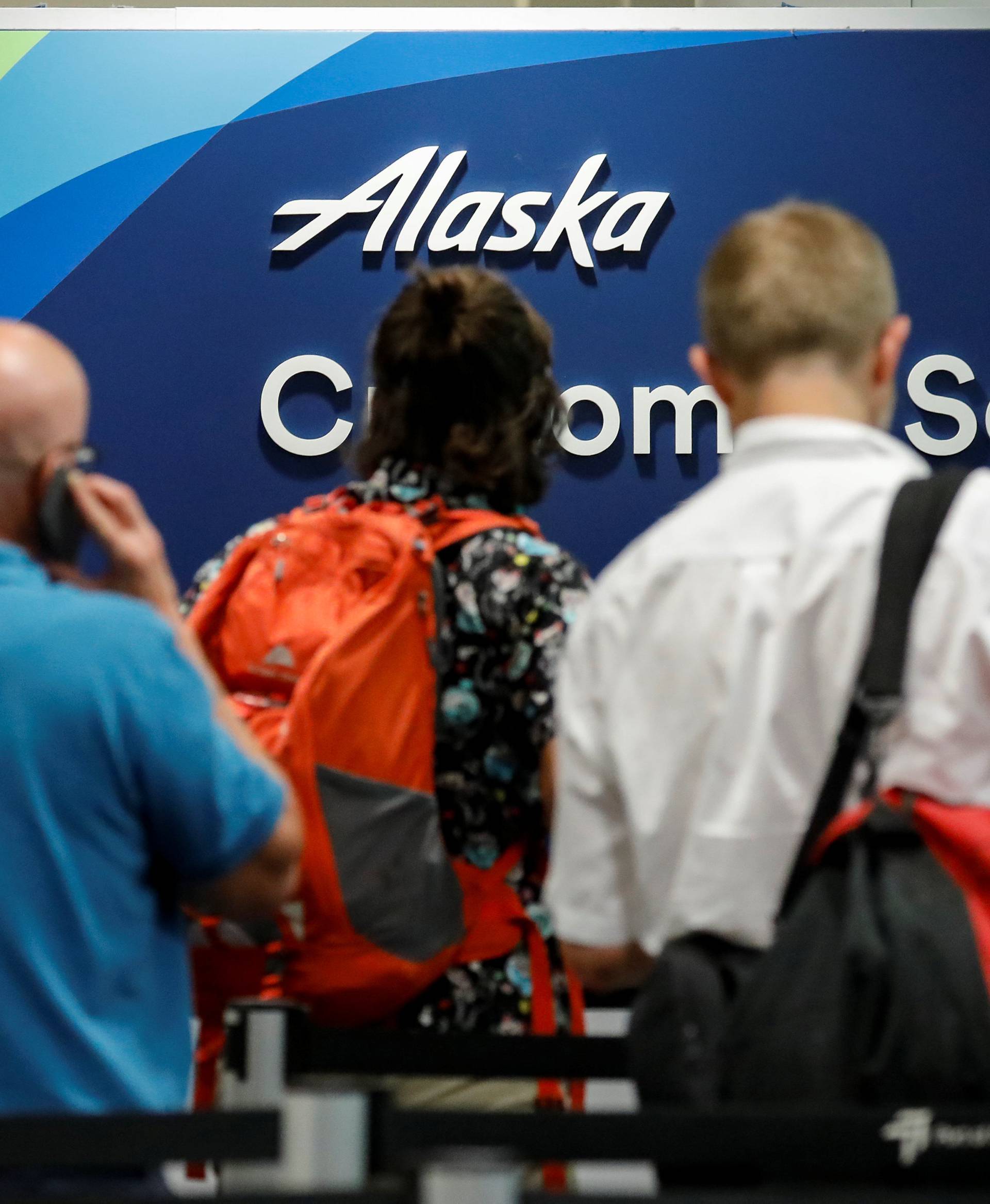 Air Alaska passengers wait at the customer service desk, following an incident where an airline employee took off in an airplane, at Seattle-Tacoma International Airport in Seattle, Washington