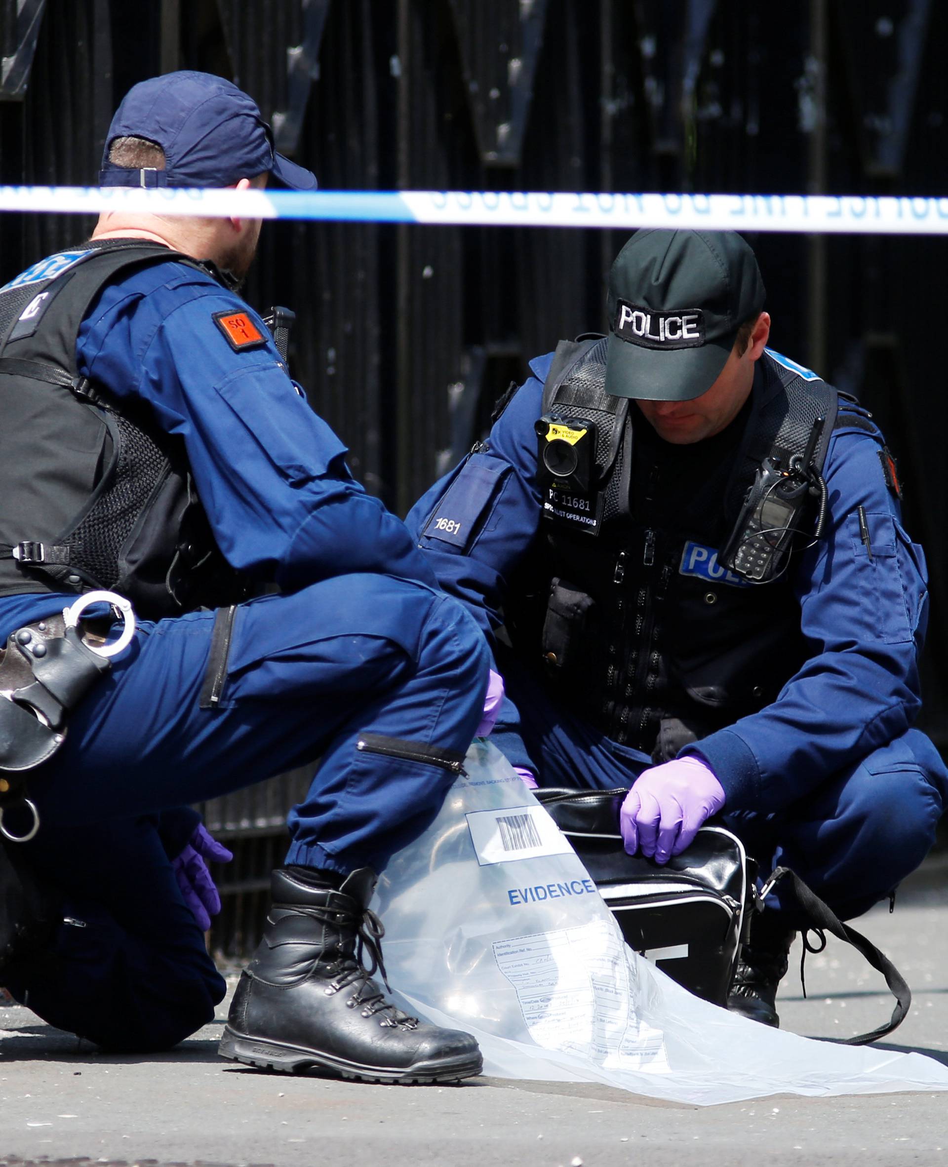 Police officers search a Nike bag in Hulme, Manchester