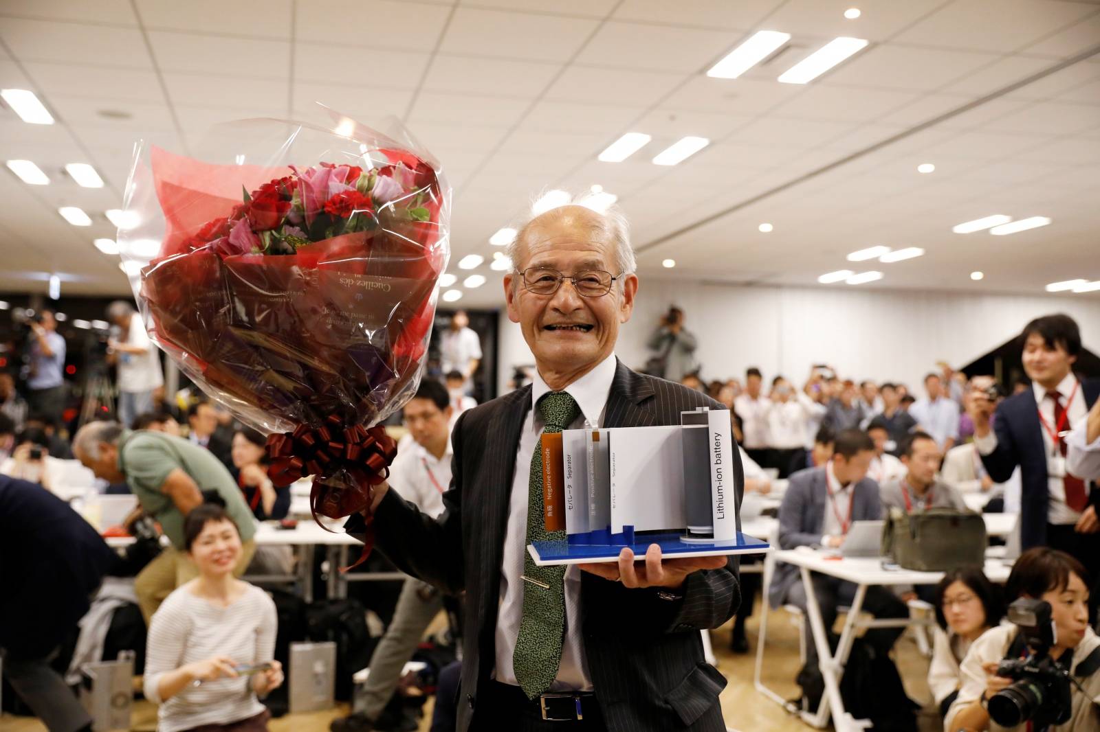 Asahi Kasei honorary fellow Akira Yoshino, 2019 Nobel Prize in Chemistry winner, holds a mock of lithium-ion battery and a flower bouquet during a news conference in Tokyo