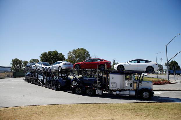 A car carrier trailer carries Tesla Model 3 electric sedans, is seen outside the Tesla factory in Fremont