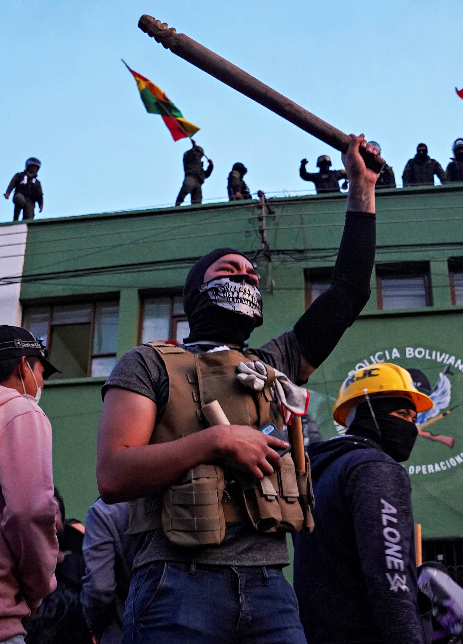 Opponents to Bolivia's President Evo Morales react as police officers stand on the roof of their headquarters, in Cochabamba