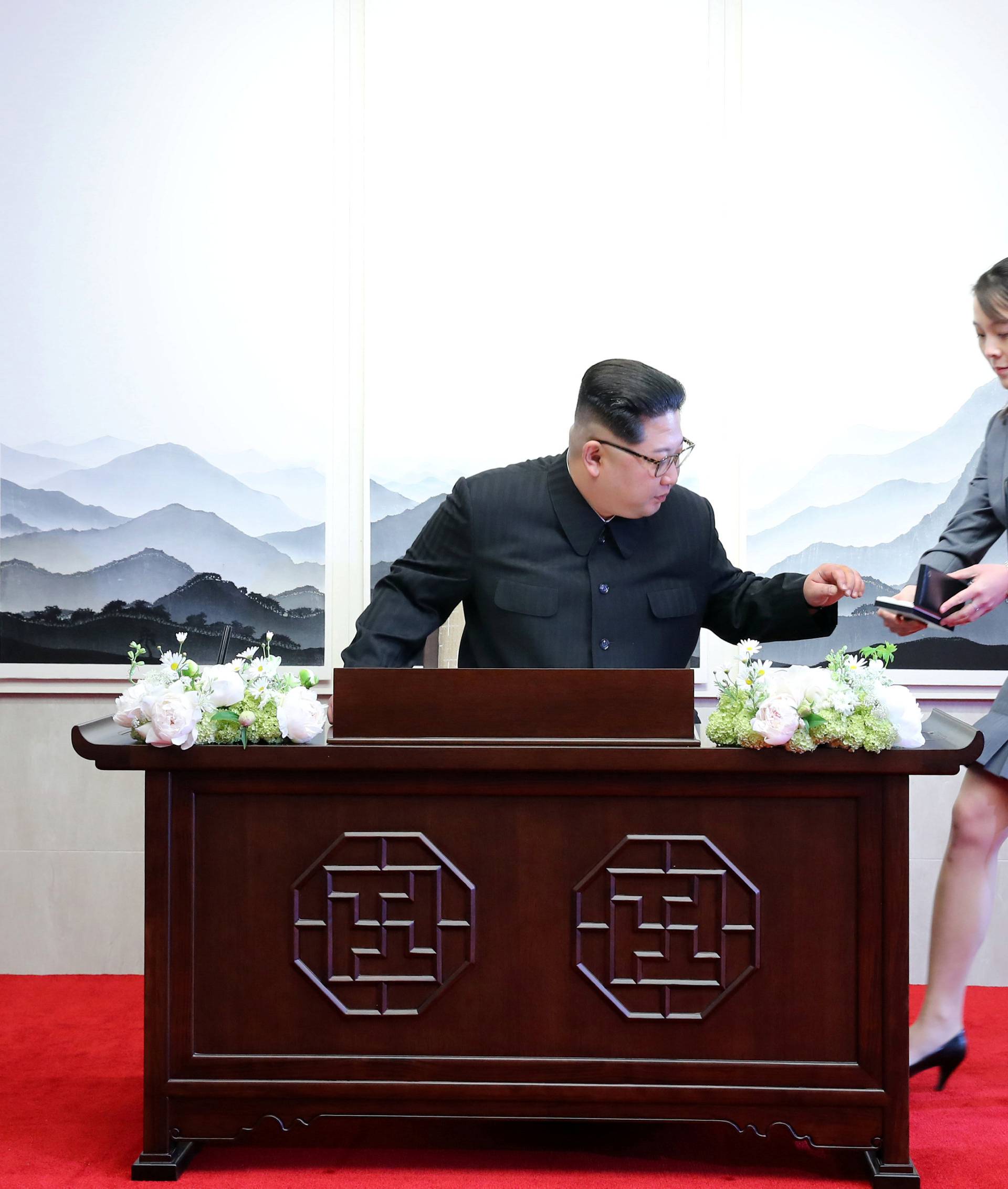 South Korean President Moon Jae-in watches as North Korean leader Kim Jong Un prepares to write in a guestbook with his sister Kim Yo Jong during their meeting at the Peace House