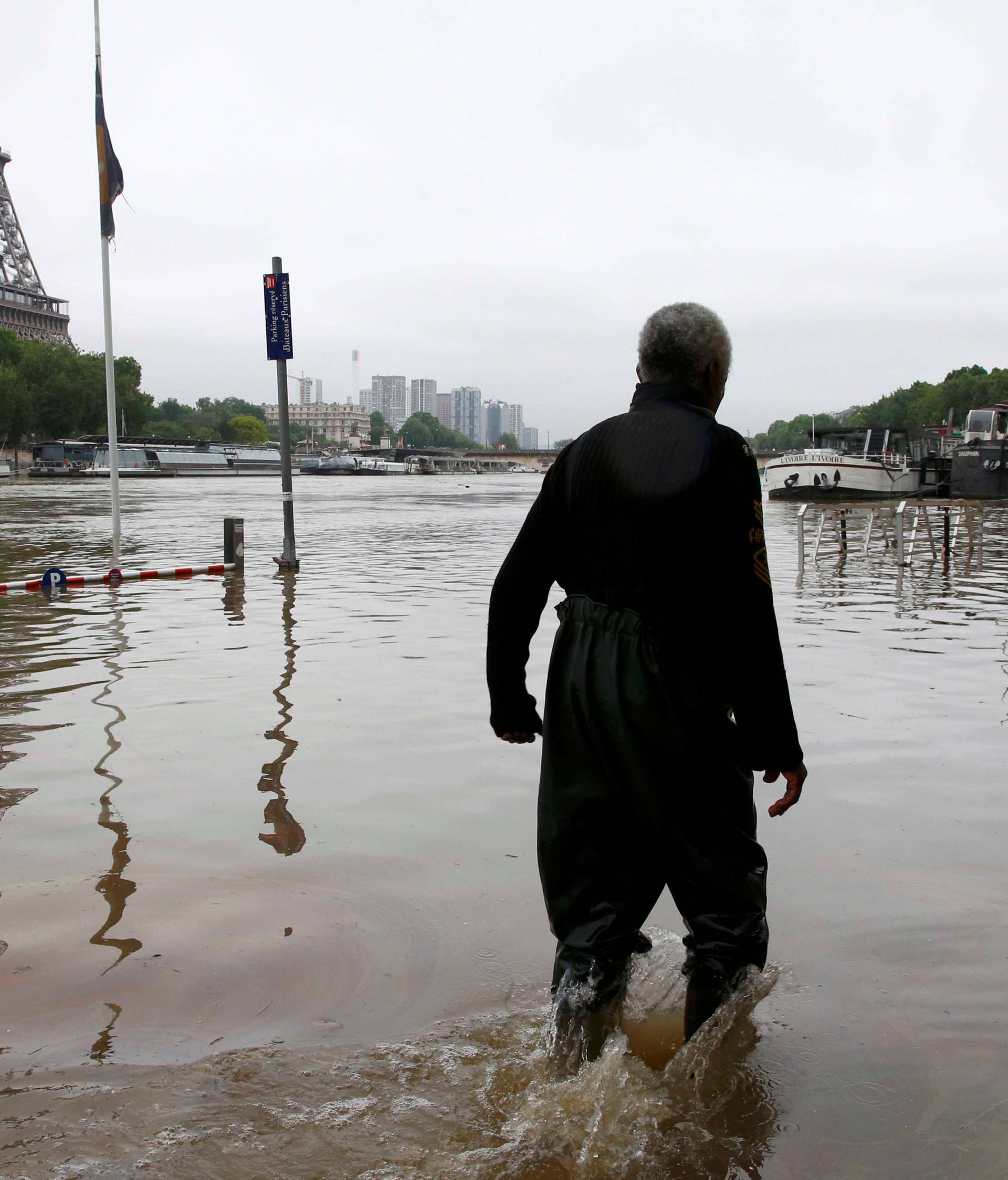 A man walks on a flooded road near his houseboat moored near the Eiffel towel during flooding on the banks of the Seine River in Paris