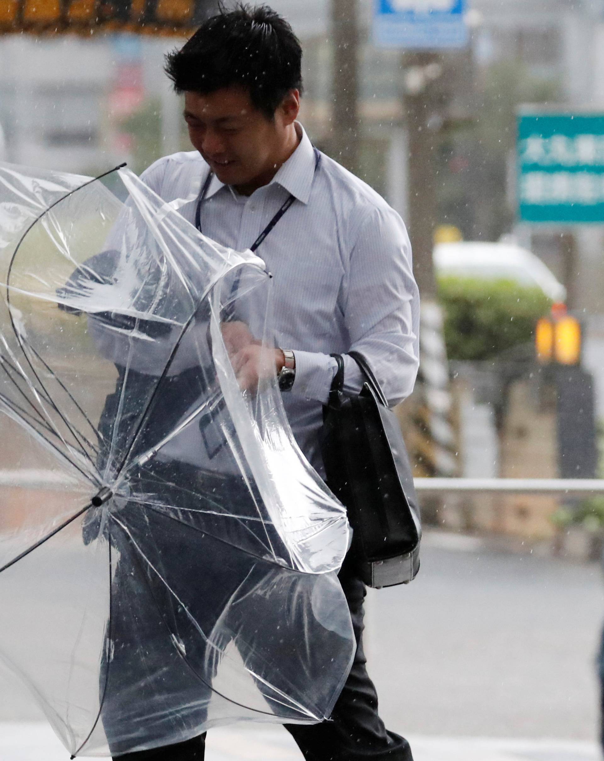 A man using an umbrella struggles against strong wind and rain caused by Typhoon Jebi, in Tokyo