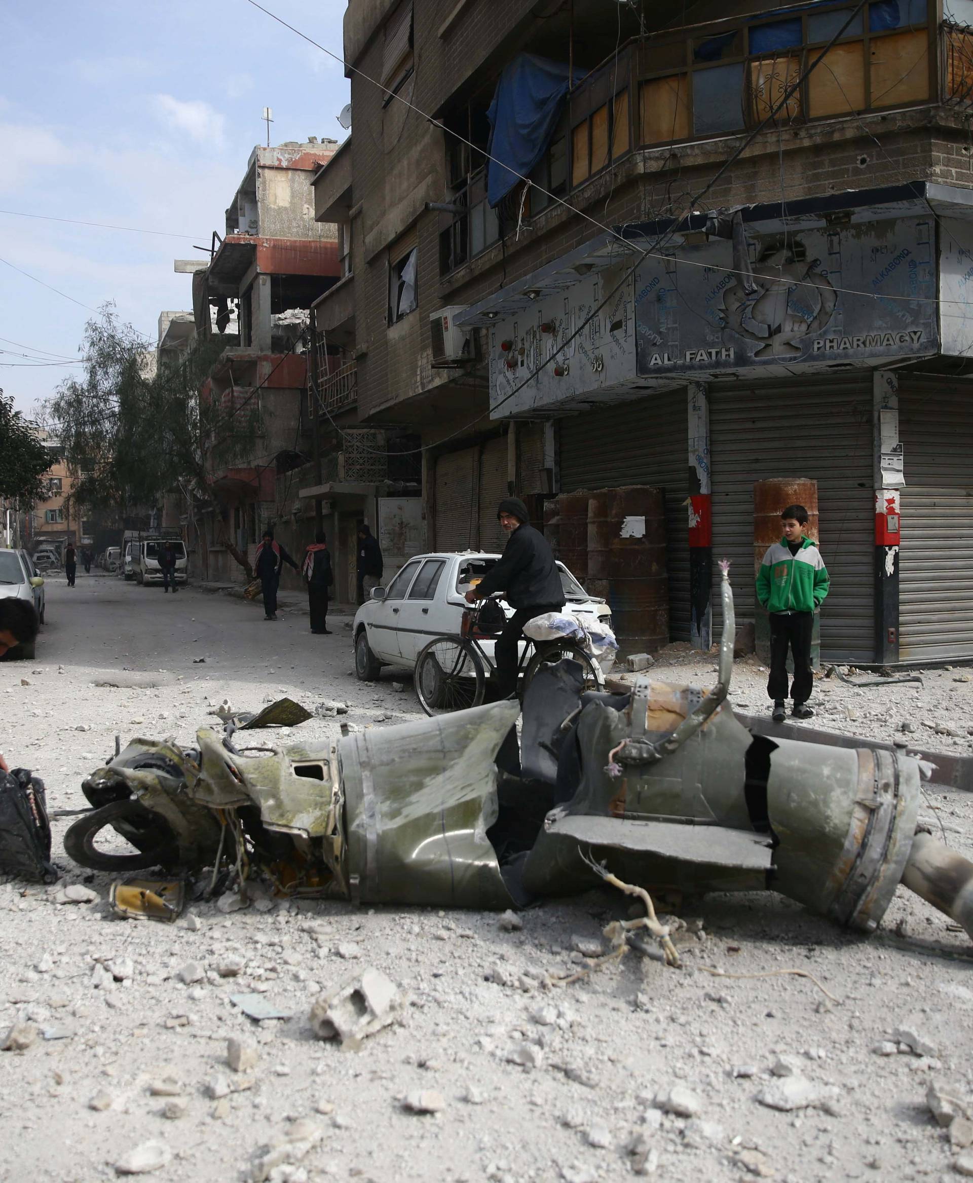 People inspect missile remains in the besieged town of Douma, in eastern Ghouta, in Damascus