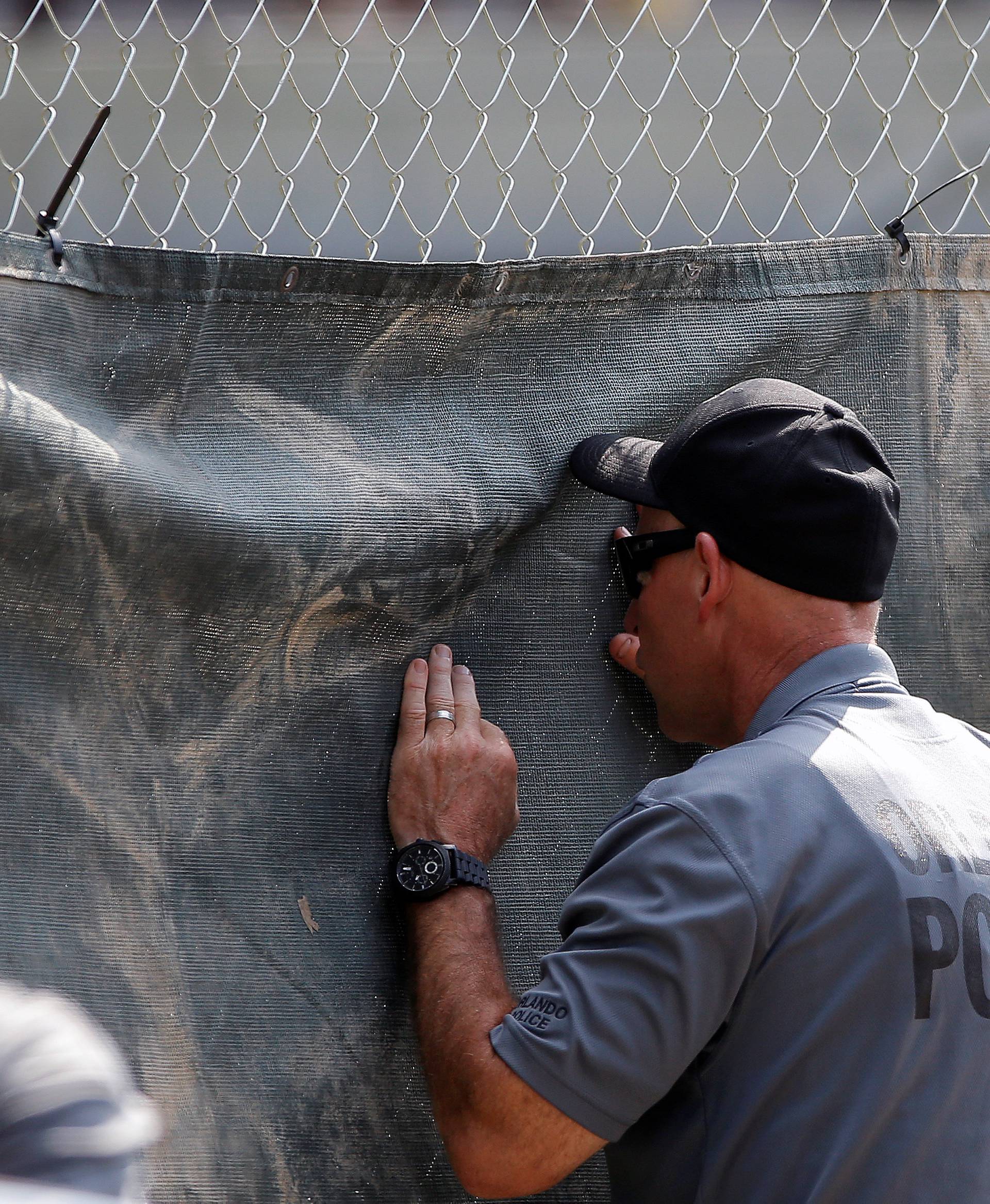 Policemen look through the fencing surrounding the crime scene of a mass shooting at the Pulse gay night club in Orlando