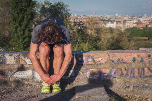 Long haired athlete stretching in a city park